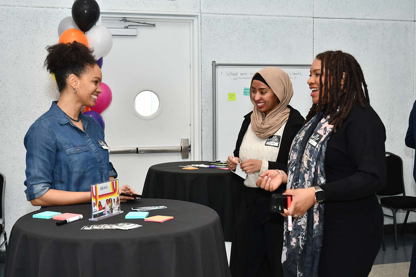 People standing by high top tables, speaking with each other and smiling at the Black at UTM launch event