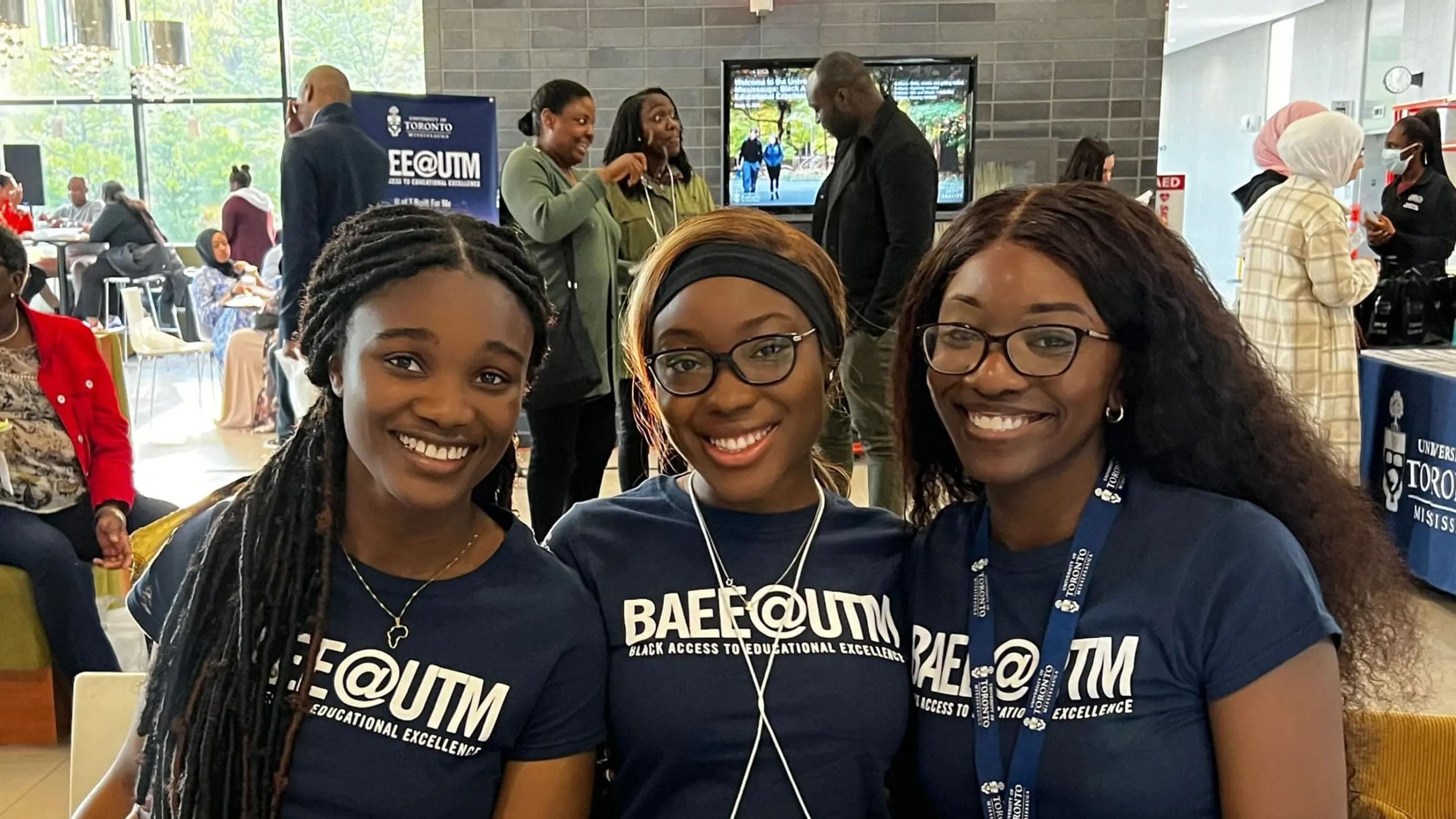 3 female students, smiling at camera and wearing BAEE shirts